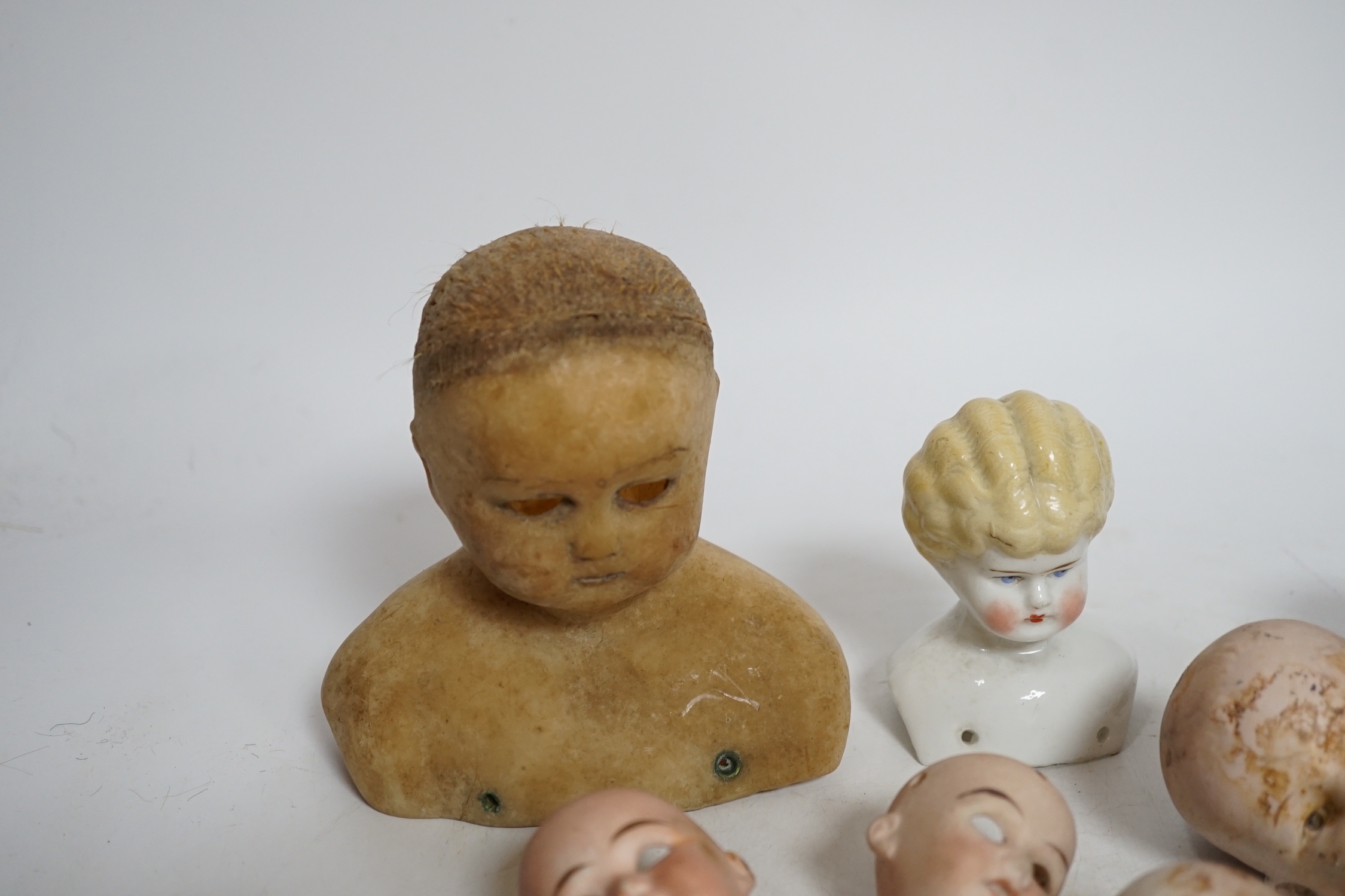 Twelve small bisque doll heads and a wax head